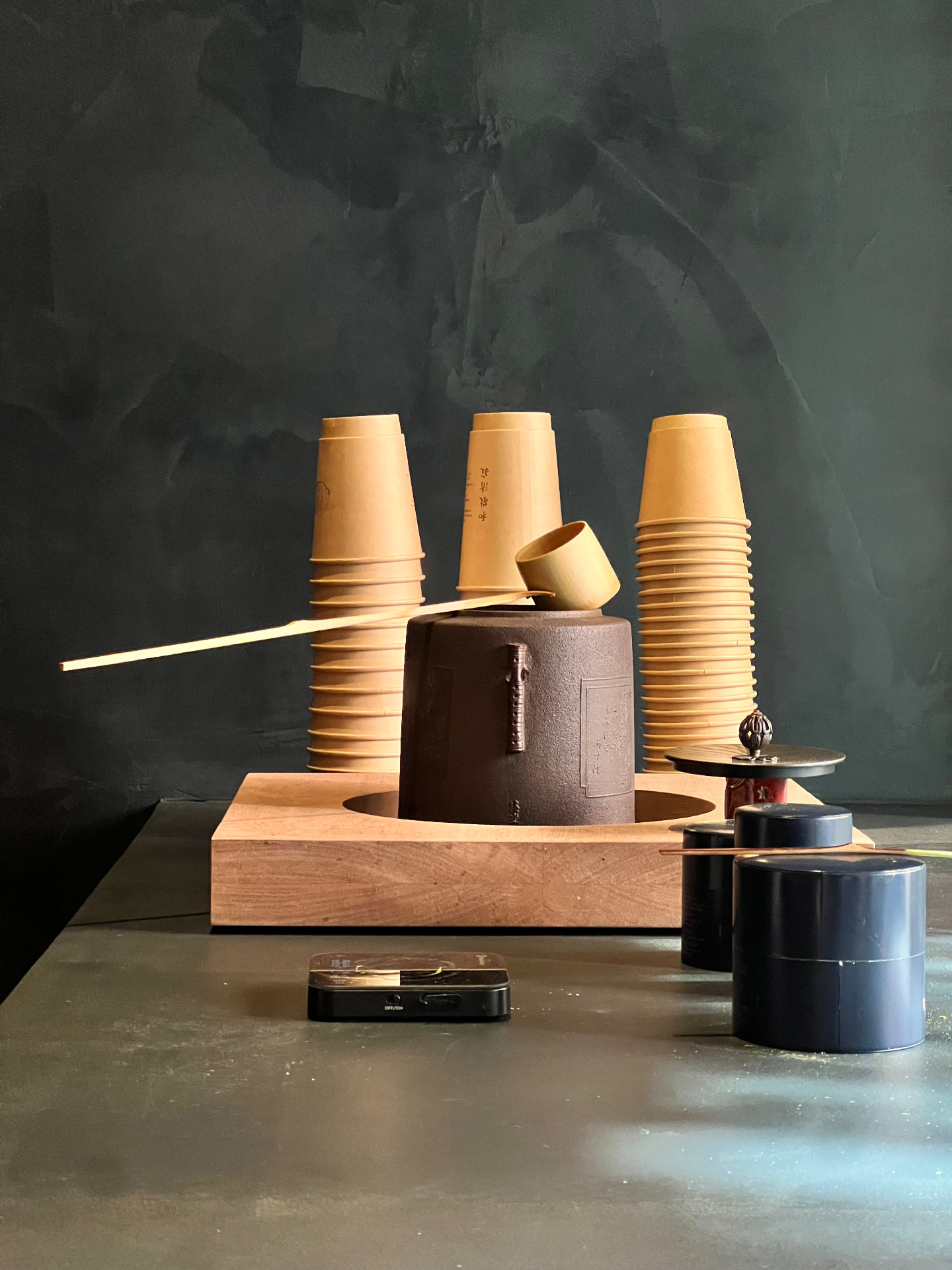 Stacked paper cups and a coffee grinder on a dark counter
